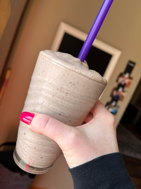 A photo of Nicky's Shakeology drink in a glass with a purple straw.