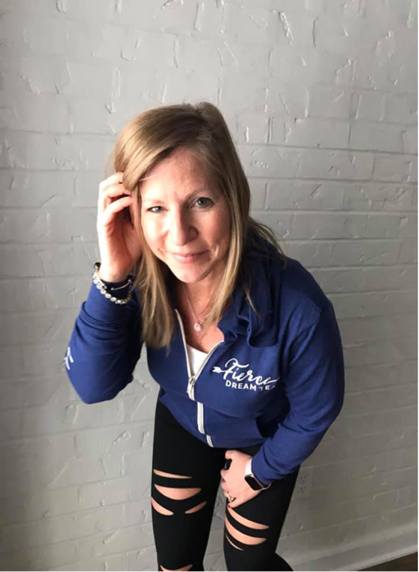 Photo of Nicky posing as she tucks her hair behind her ear.